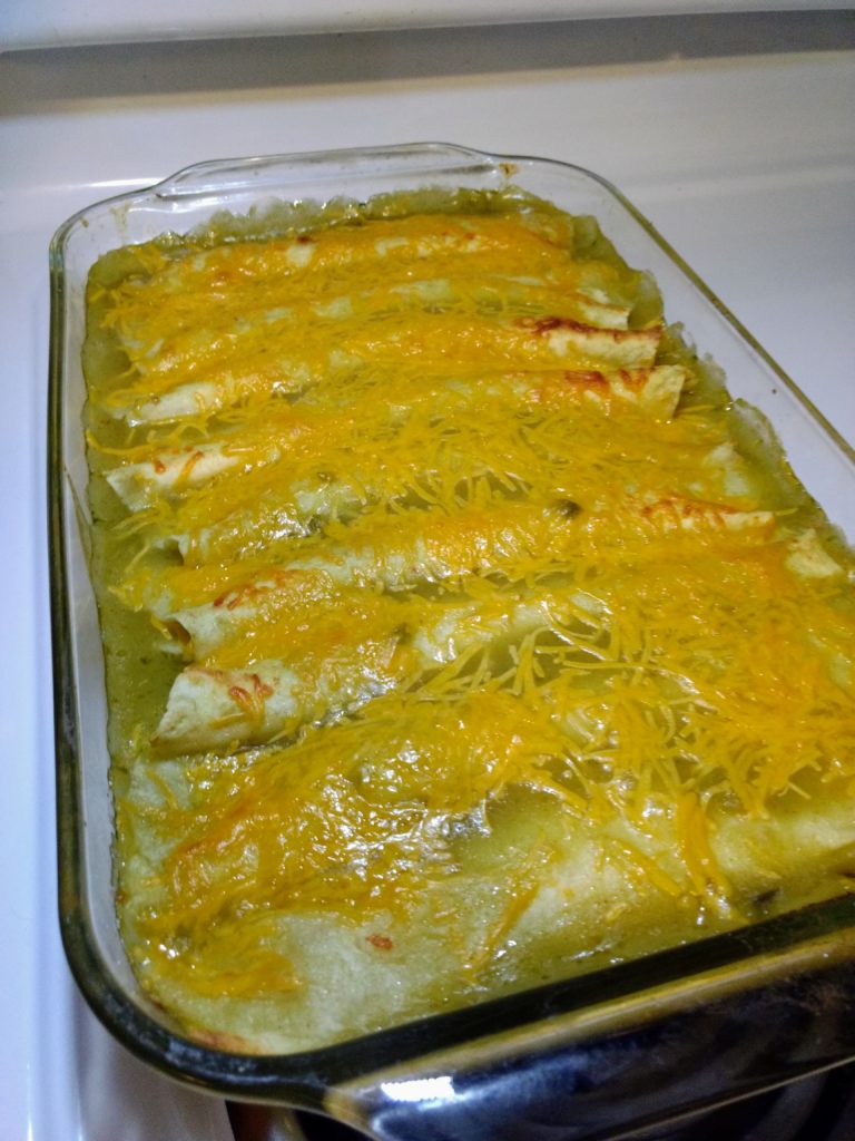 creamy baked green chili chicken enchiladas in pan